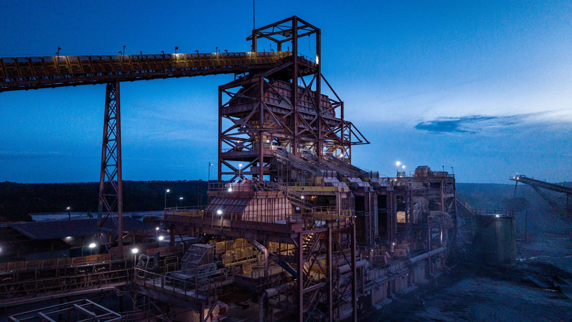Complexo mínero-industrial de Pitinga iluminado ao anoitecer, sob céu azul